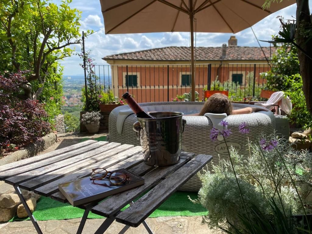 A patio with a table, a metal bucket, and a person reclining on a cushioned chair.