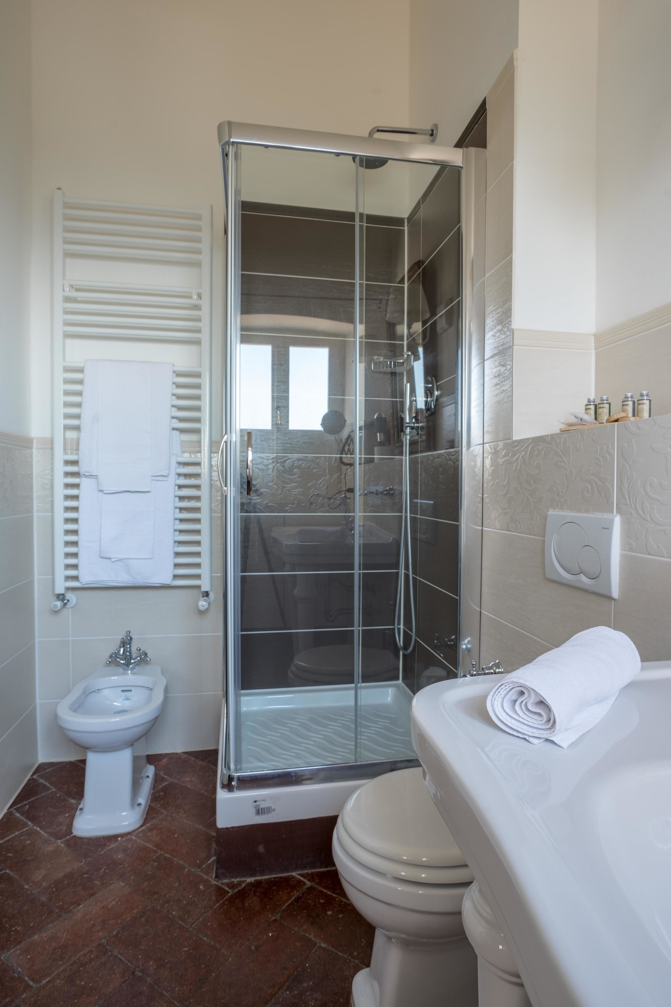 A modern bathroom with a glass-enclosed shower, a toilet, and a bidet.