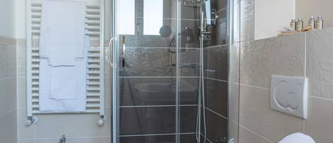 A modern bathroom with a glass-enclosed shower, a toilet, and a bidet.