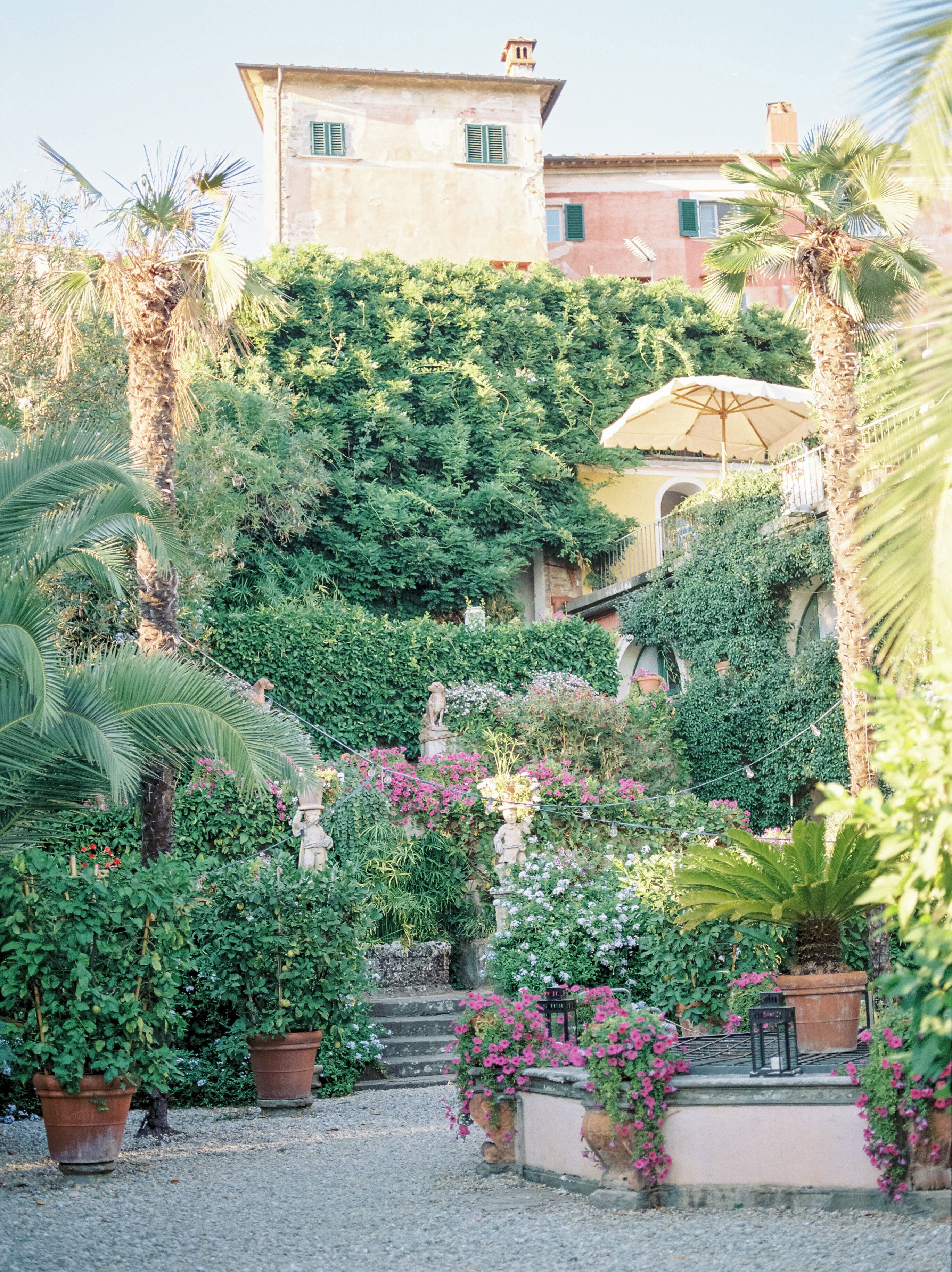 A garden with potted plants, a statue, and a building in the background.
