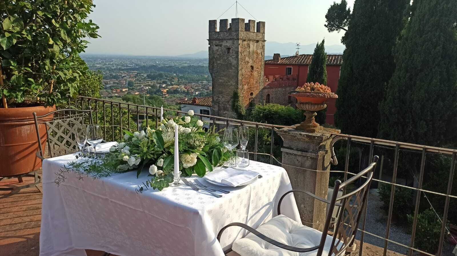 A table set for dining with a view of a historic tower and distant landscape.