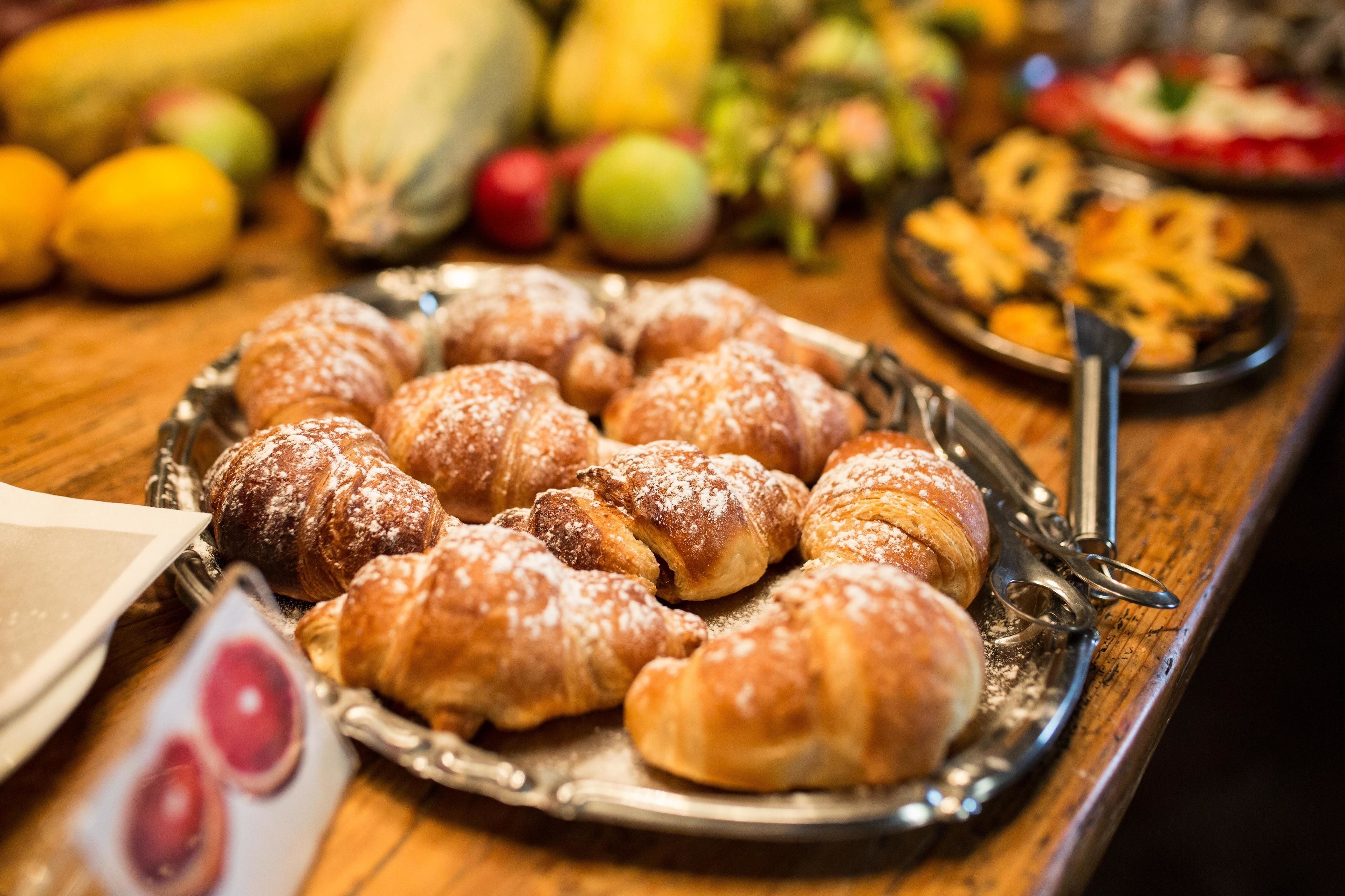 A tray of pastries on a table with various fruits and vegetables in the background.