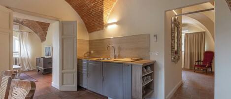 A kitchen with a wooden countertop, grey cabinets, and a brick ceiling.