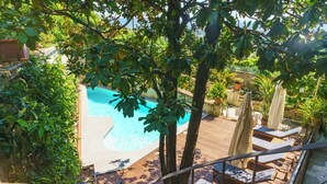 Una piscina con cubierta de madera, sillas de descanso y plantas en macetas.