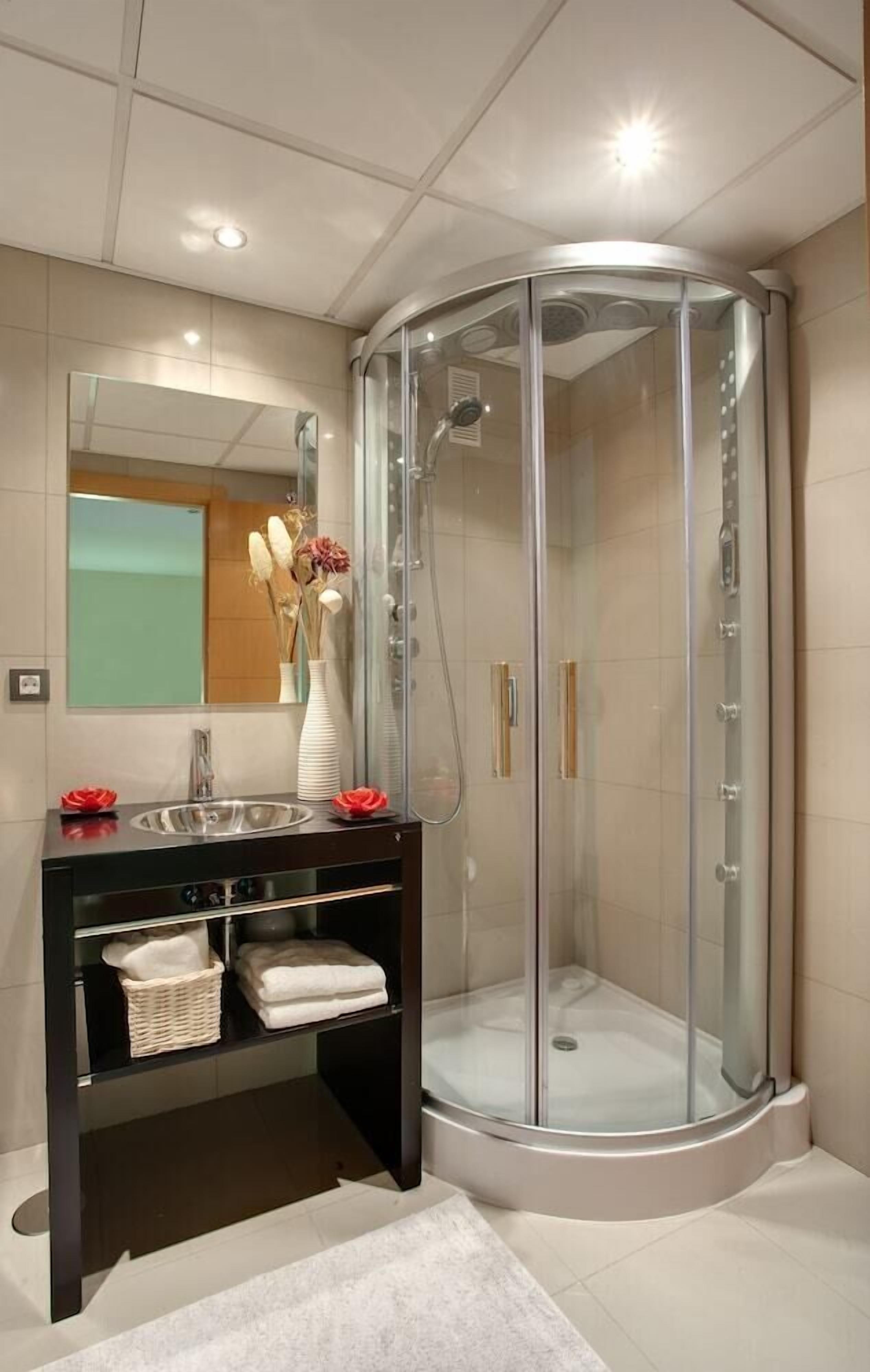 A modern bathroom with a glass-enclosed shower, a vanity with a mirror, and a white sink.