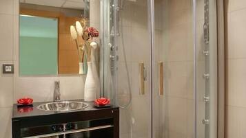 A modern bathroom with a glass-enclosed shower, a vanity with a mirror, and a white sink.