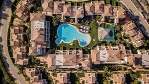An aerial view of a residential area with a central swimming pool surrounded by houses. -  Apartamentos Cortijo del Mar Resort (Estepona)