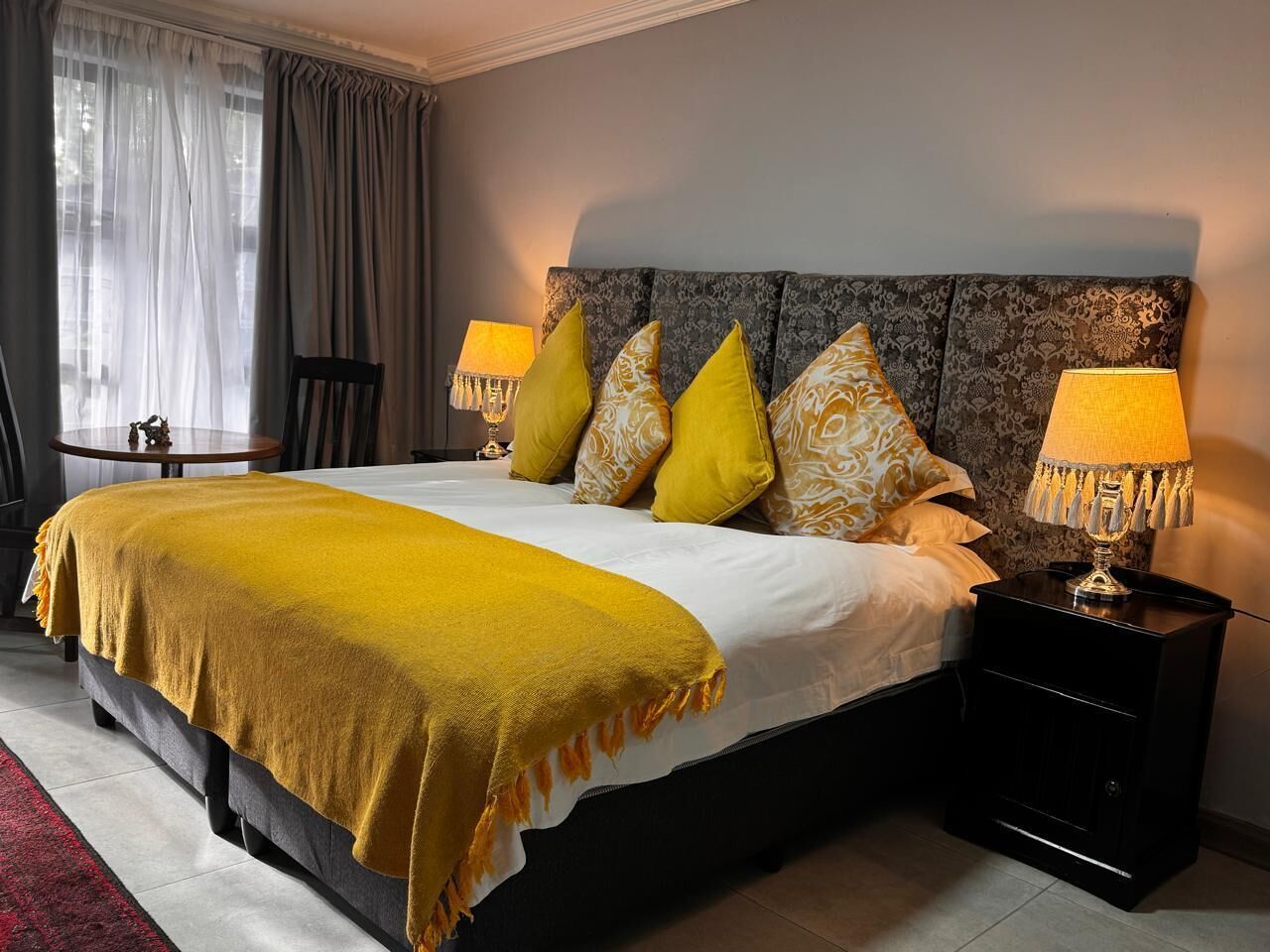 A hotel room with a large bed, two bedside lamps, and a nightstand.