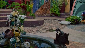 Un patio con una fuente, plantas en macetas y una escultura decorativa de metal.