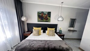 Une chambre d’hôtel avec un grand lit, deux tables de chevet, un tableau au mur et une petite étagère sur laquelle se trouve un vase.