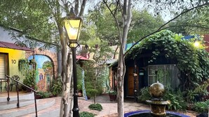 Une cour avec une fontaine, un escalier et un lampadaire.