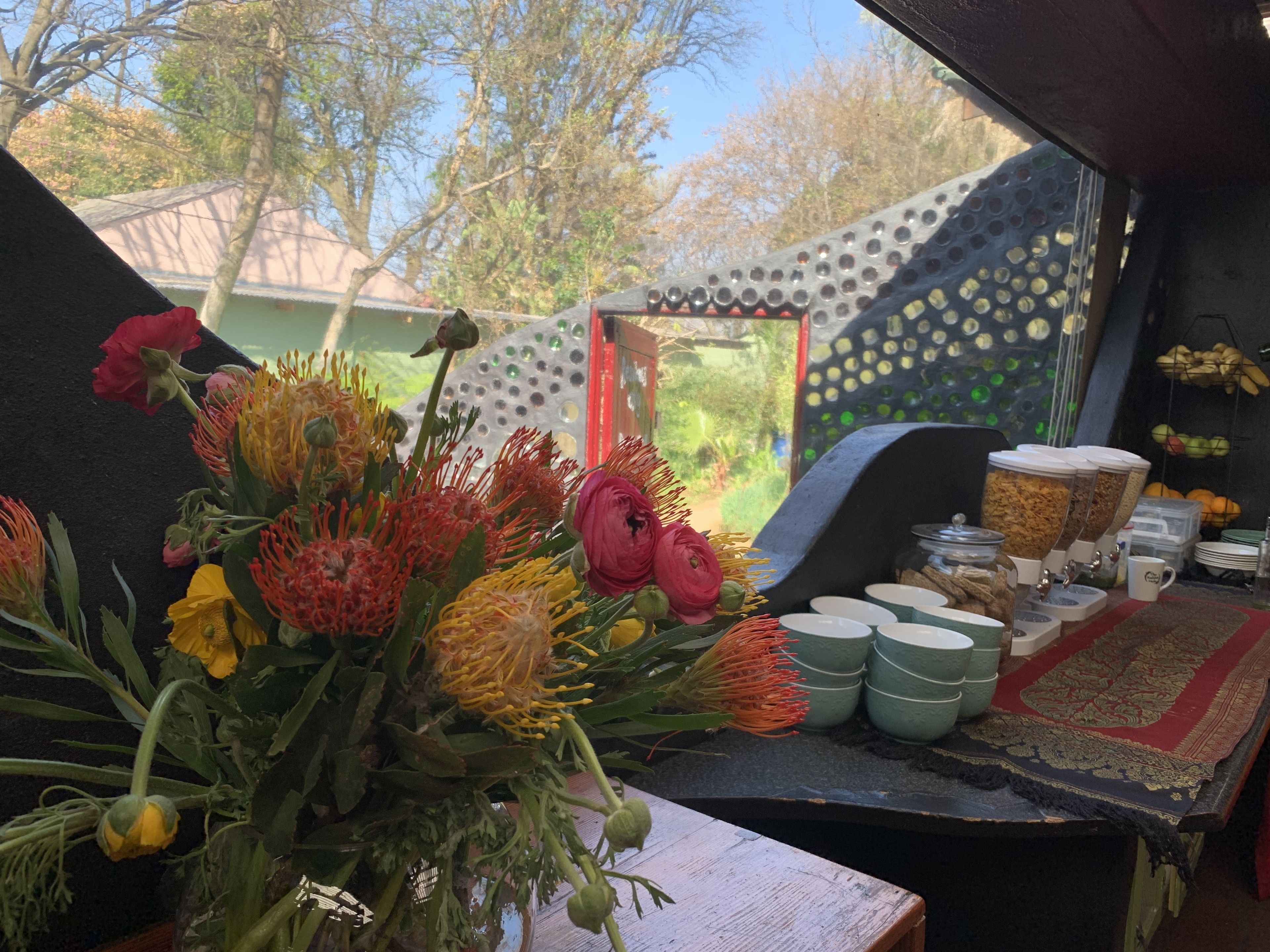 Una habitación con una mesa que exhibe una variedad de flores y una estación de café con dispensadores y tazas.