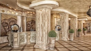 A reception area with marble columns, a check-in counter, and a check-out counter. - Royal Bay Hotel – All Inclusive (Elenite)