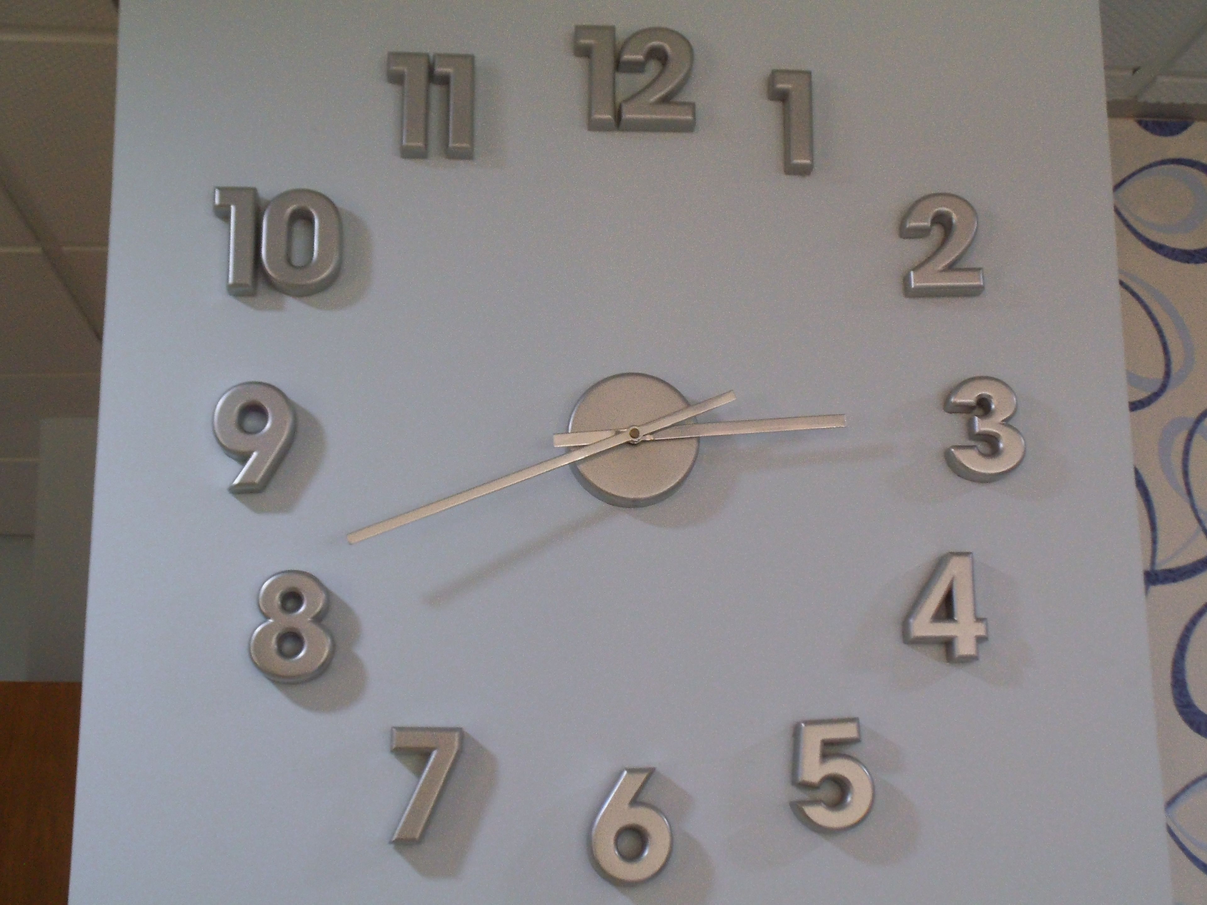 A wall clock with a minimalist design, featuring numbers 1 through 12 and a second hand.