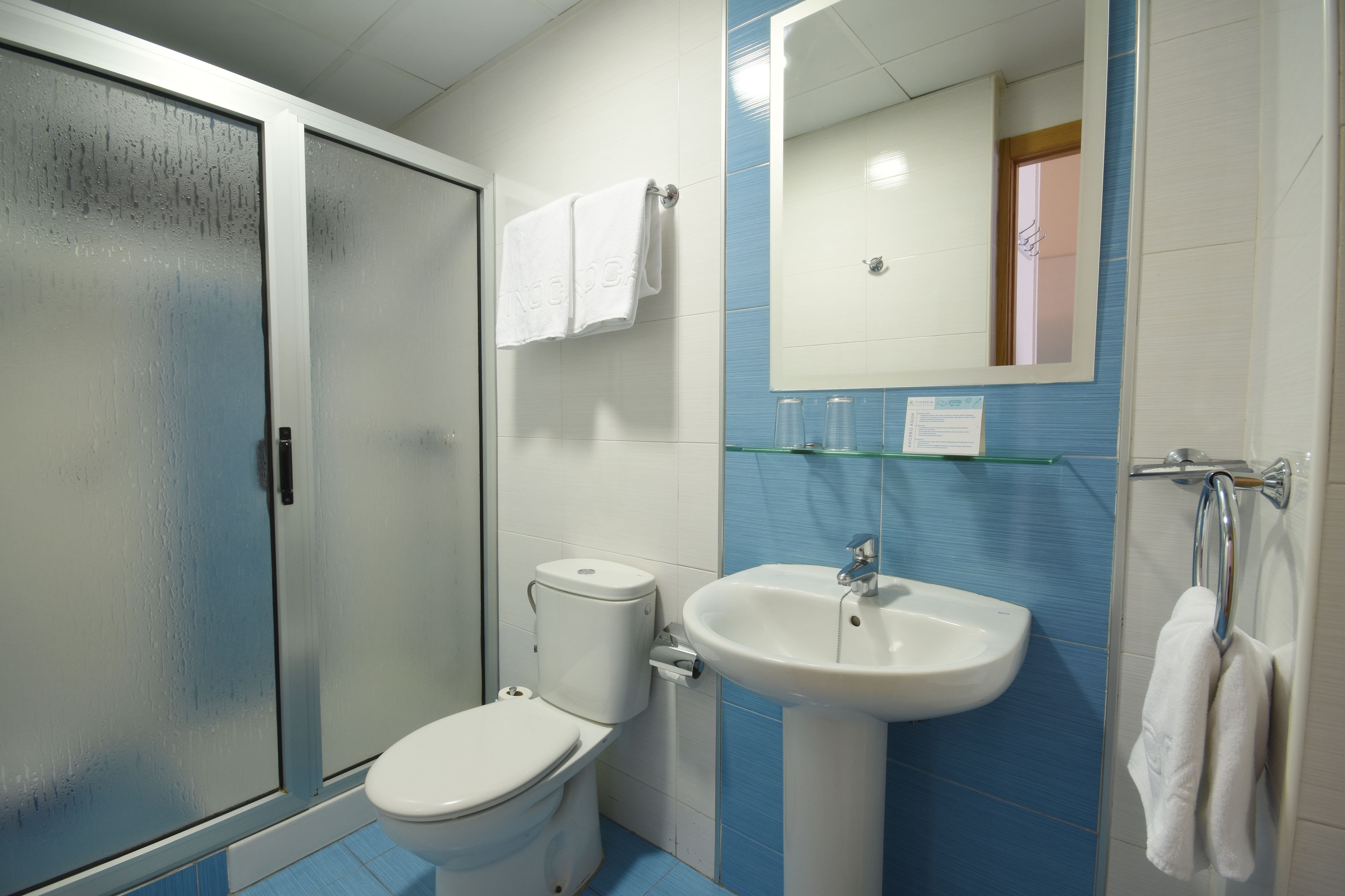 Un baño con inodoro, lavamanos y cabina de ducha de vidrio.