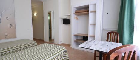 A room with two beds, a table, chairs, a TV, and a wardrobe.