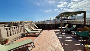 Terraza en la azotea con sillones de descanso y una zona de estar cubierta, que ofrece vistas panorámicas de la ciudad.