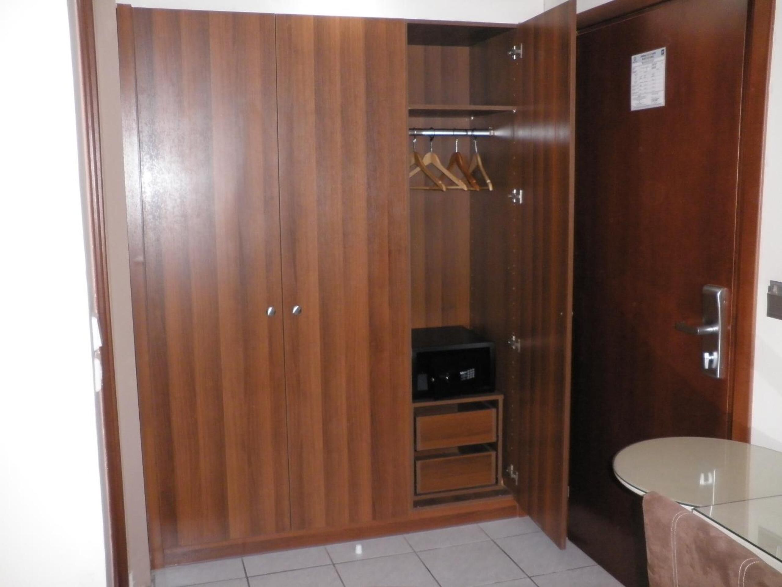 Un armario de madera con espejo, un estante pequeño y una barra para colgar ropa.