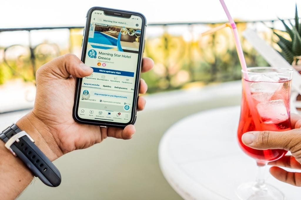 A person holding a smartphone displaying a hotel booking page for the Morning Star Hotel in Greece.