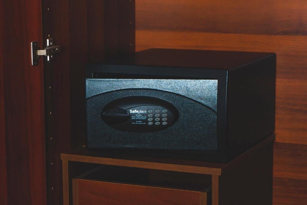 Una caja fuerte negra con teclado y la palabra 'SafePlace' en la pantalla, sobre un mueble de madera.