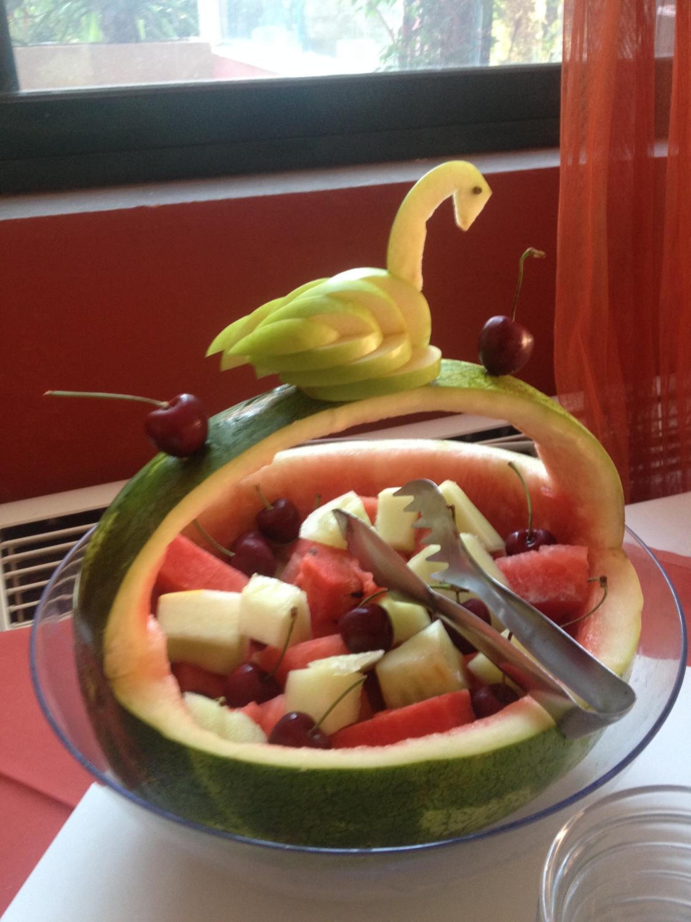 A fruit salad in a bowl with a decorative fruit arrangement on top.