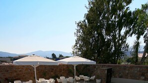 Une piscine rectangulaire bordée de carreaux, entourée d’un mur de briques et d’une terrasse également carrelée, avec des chaises blanches et une table.