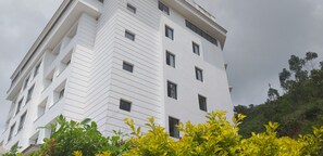 A multi-story building with a modern architectural design, featuring a series of windows and balconies. - Clouds Valley Leisure Hotel (Devikolam)