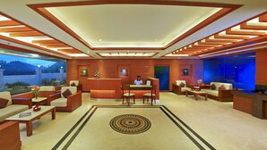 A hotel lobby with a reception desk, seating area, and a large window overlooking a scenic view. - Clouds Valley Leisure Hotel (Devikolam)