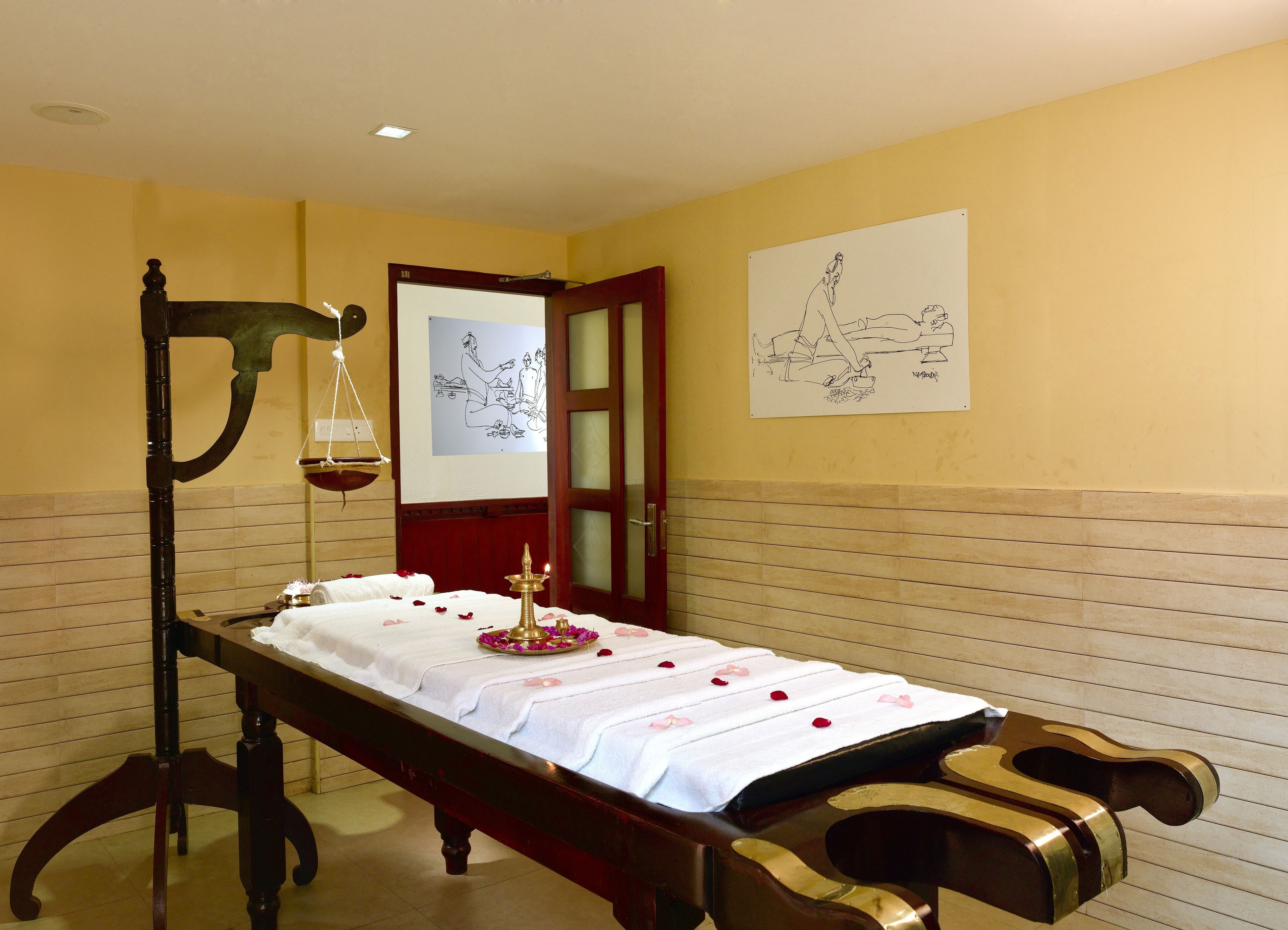 A room with a bed, a hanging scale, a whiteboard with drawings, and a door.