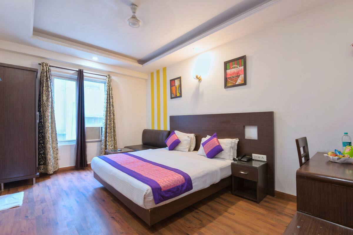 A hotel room with a large bed, bedside tables, a desk, and a wardrobe.