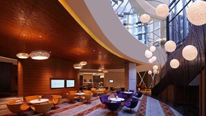A spacious lobby with modern furniture, a large screen, and a high ceiling with hanging spherical lights. - Hotel La Vista (New Delhi)