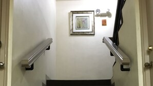 A carpeted staircase with metal handrails, a framed picture on the wall, and a door with a doorknob. - Tamuning Plaza Hotel (Tamuning)