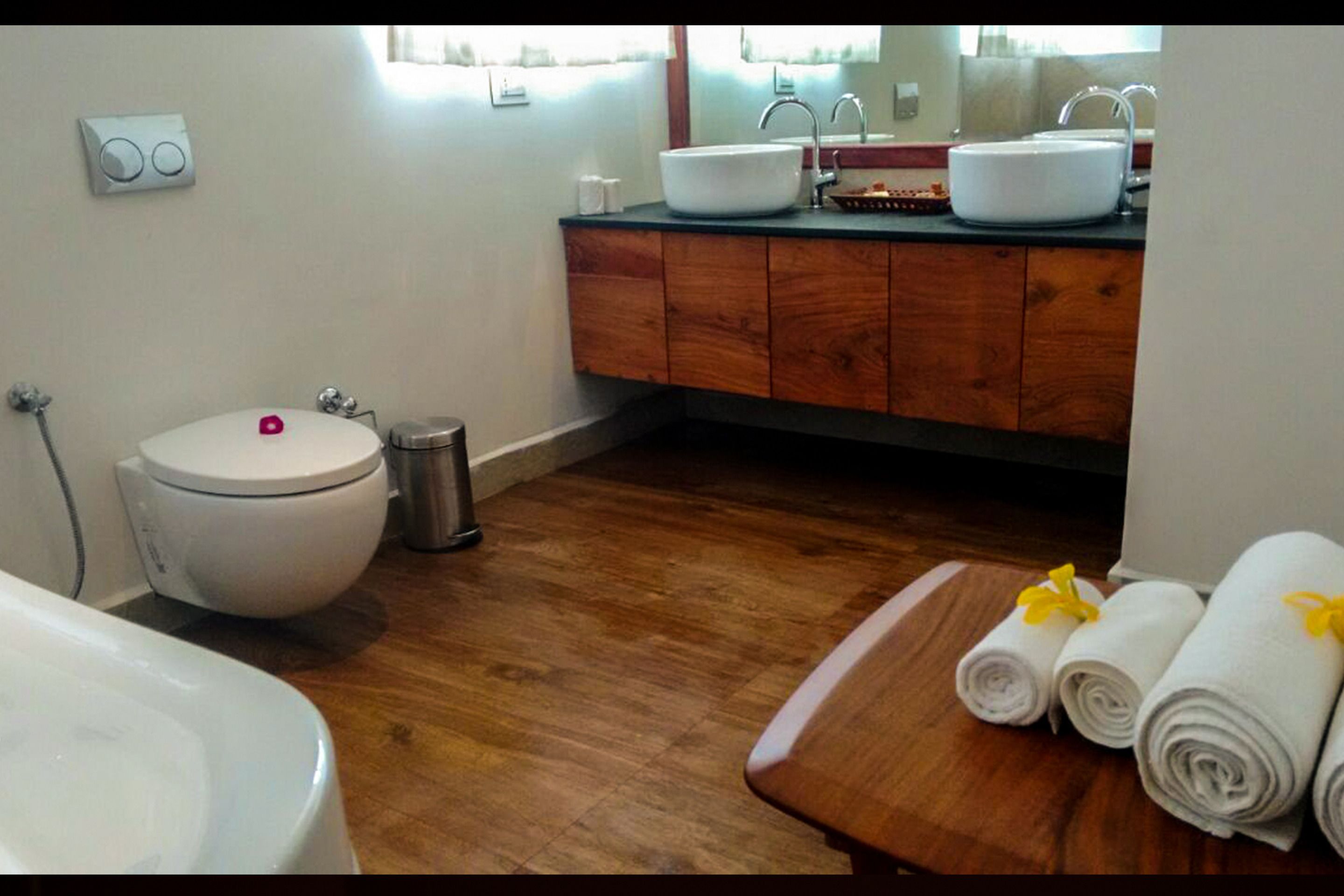 Une salle de bain équipée de toilettes, d’un lavabo et d’un meuble-lavabo en bois.