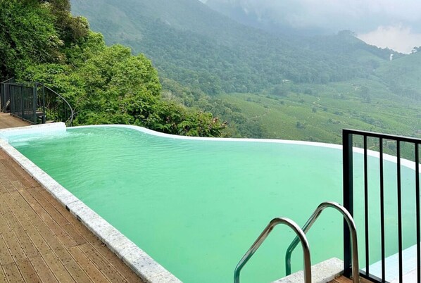 Una piscina al aire libre, sombrillas, sillones reclinables de piscina