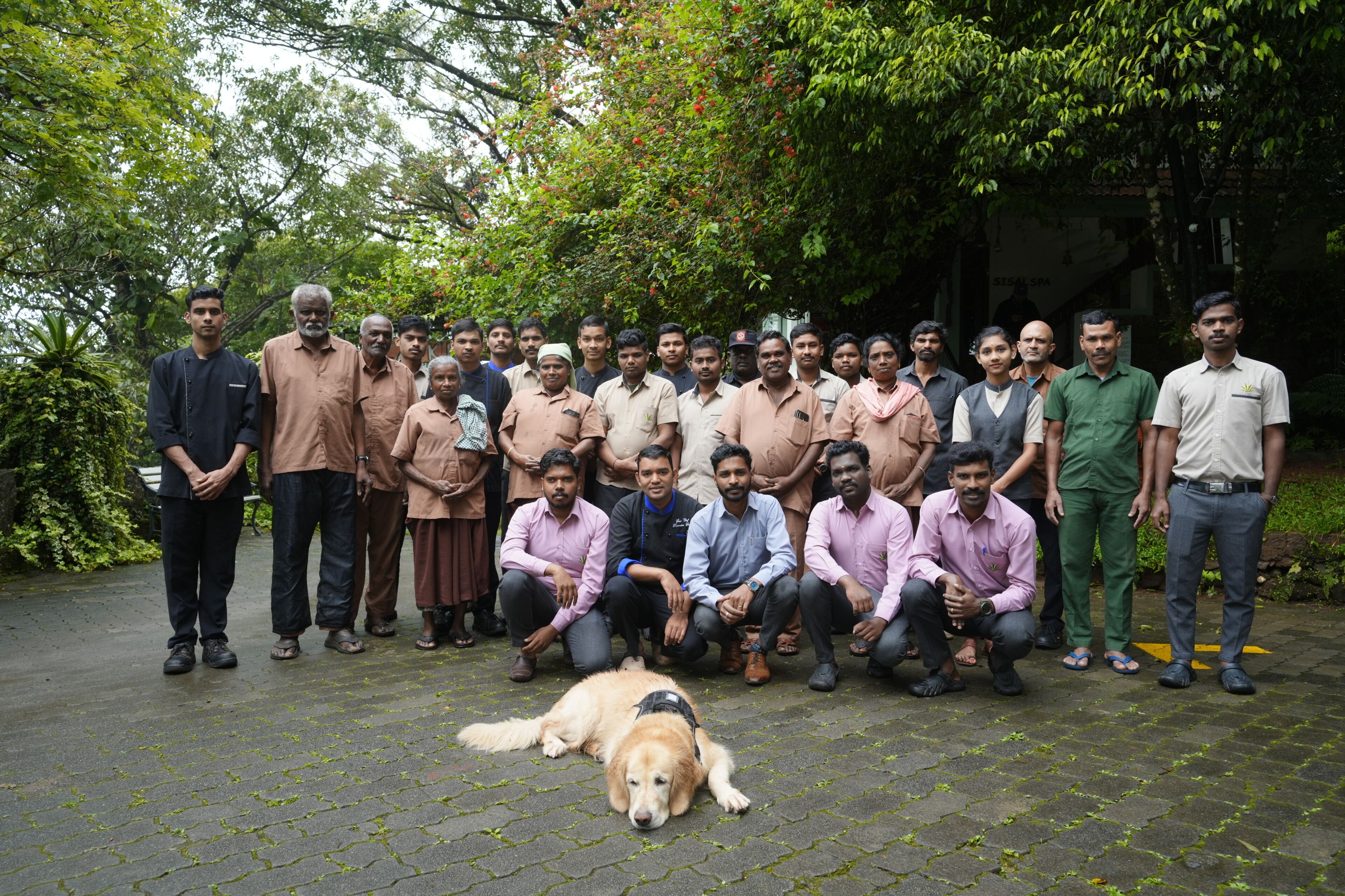 A group of people posing outdoors with a dog in the foreground.
