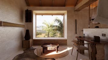 A room with a large window, a round wooden table, a chair, and a rustic wooden cabinet.