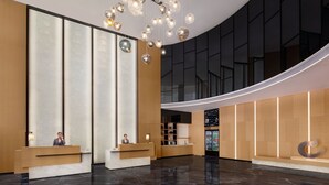 Un moderno vestíbulo de hotel con techo curvo, una recepción y un amplio muro de cristal.