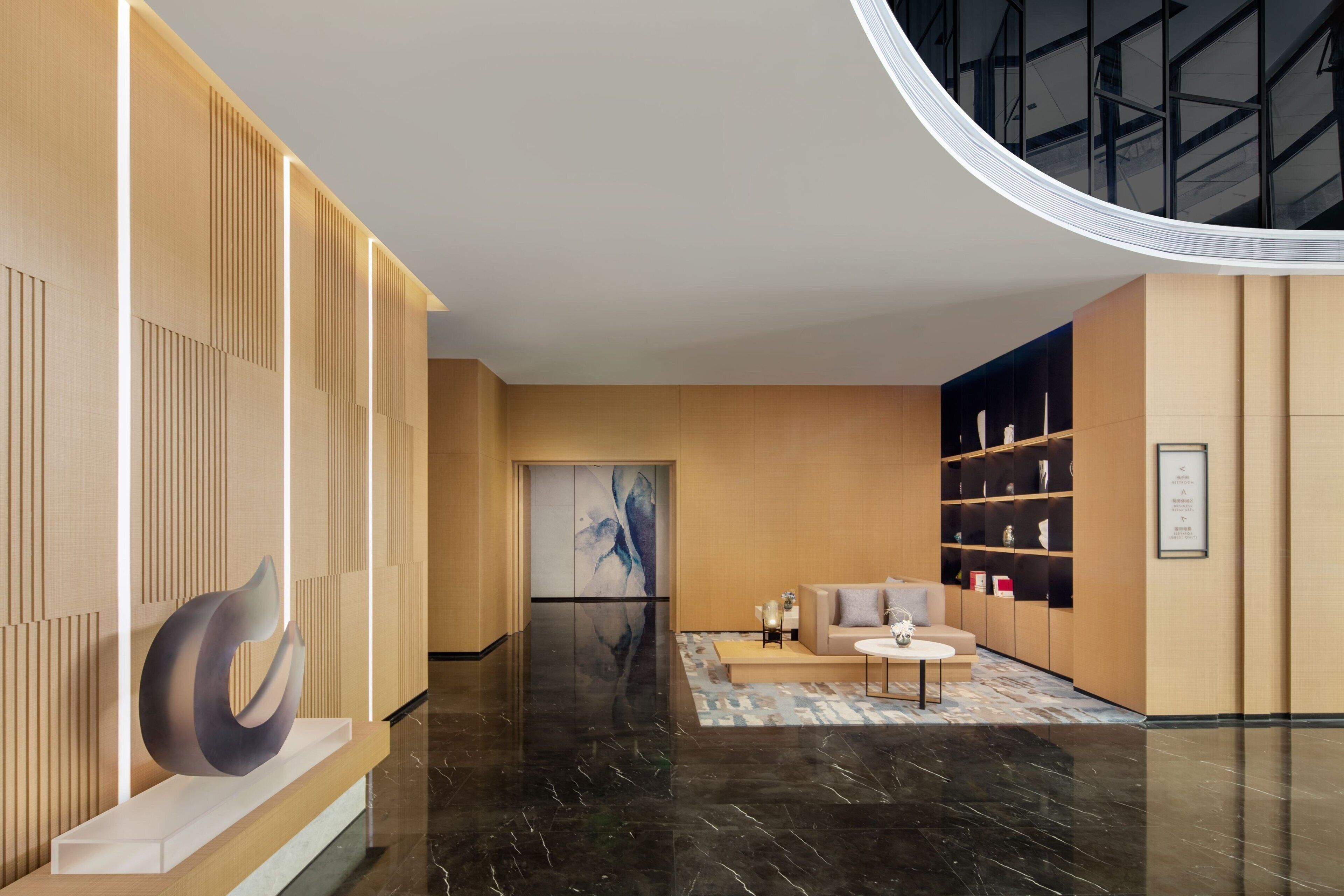 A modern lobby with a sleek reception desk, a large abstract painting, and a seating area with a coffee table.