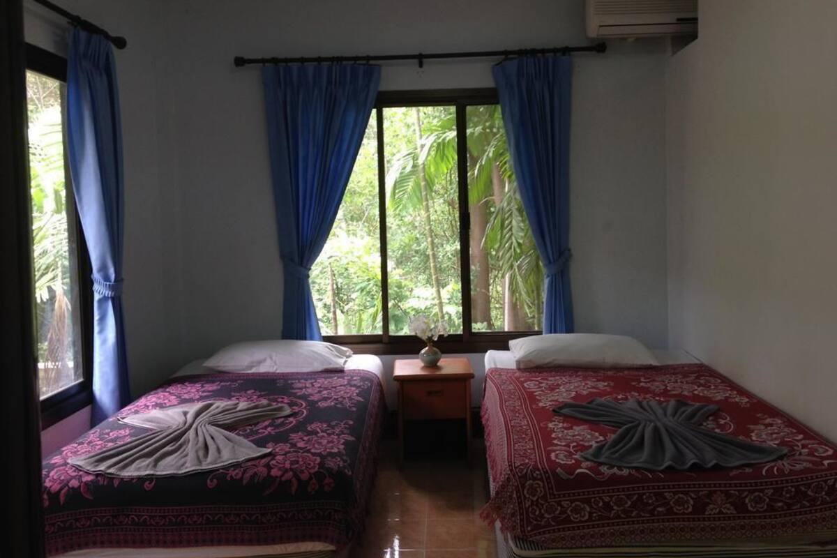 Una habitación con dos camas, una mesita y una ventana con cortinas.