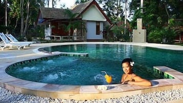 Una piscina al aire libre, sombrillas, sillones reclinables de piscina