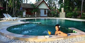 Una piscina al aire libre, sombrillas, sillones reclinables de piscina