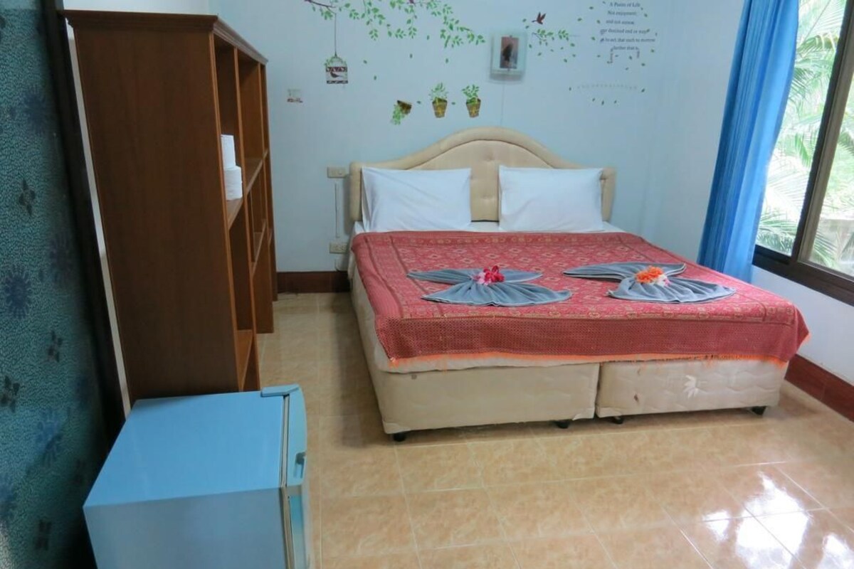 A bedroom with a bed, a wardrobe, and a small cabinet.
