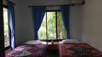 Una habitación con dos camas, una mesita y una ventana con cortinas.