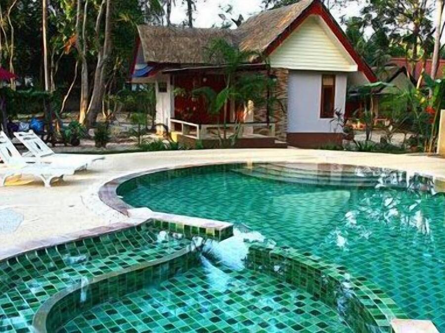 Una piscina al aire libre, sombrillas, sillones reclinables de piscina