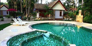 A swimming pool with a tiled edge, lounge chairs, and small buildings with thatched roofs. - Phalarn Inn Resort (Koh Samui)