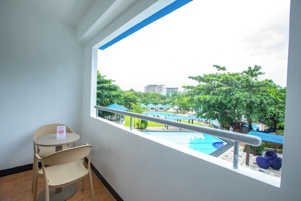 A balcony with a view of a swimming pool, a chair, and a railing.