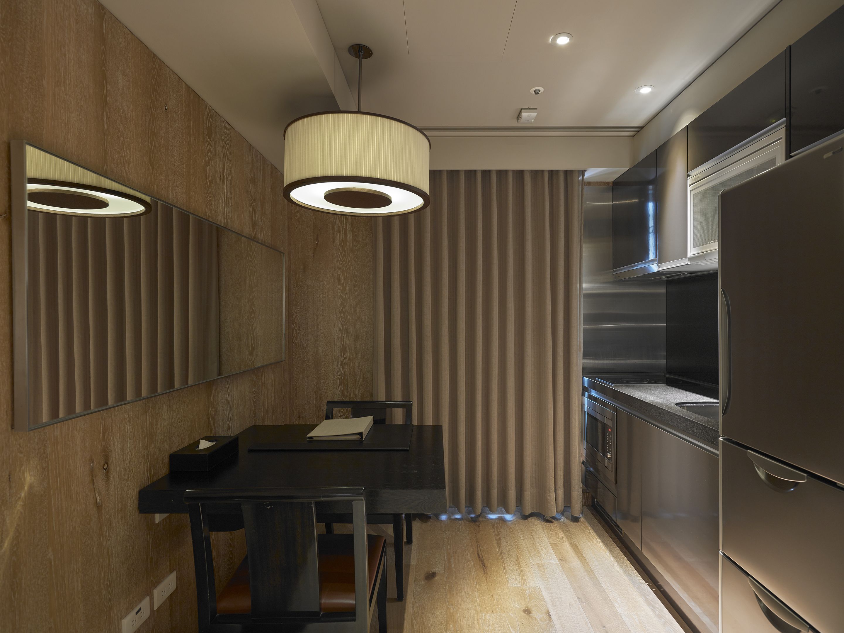 A modern kitchen with a built-in refrigerator, a dining area with a table and chairs, and a pendant light fixture.