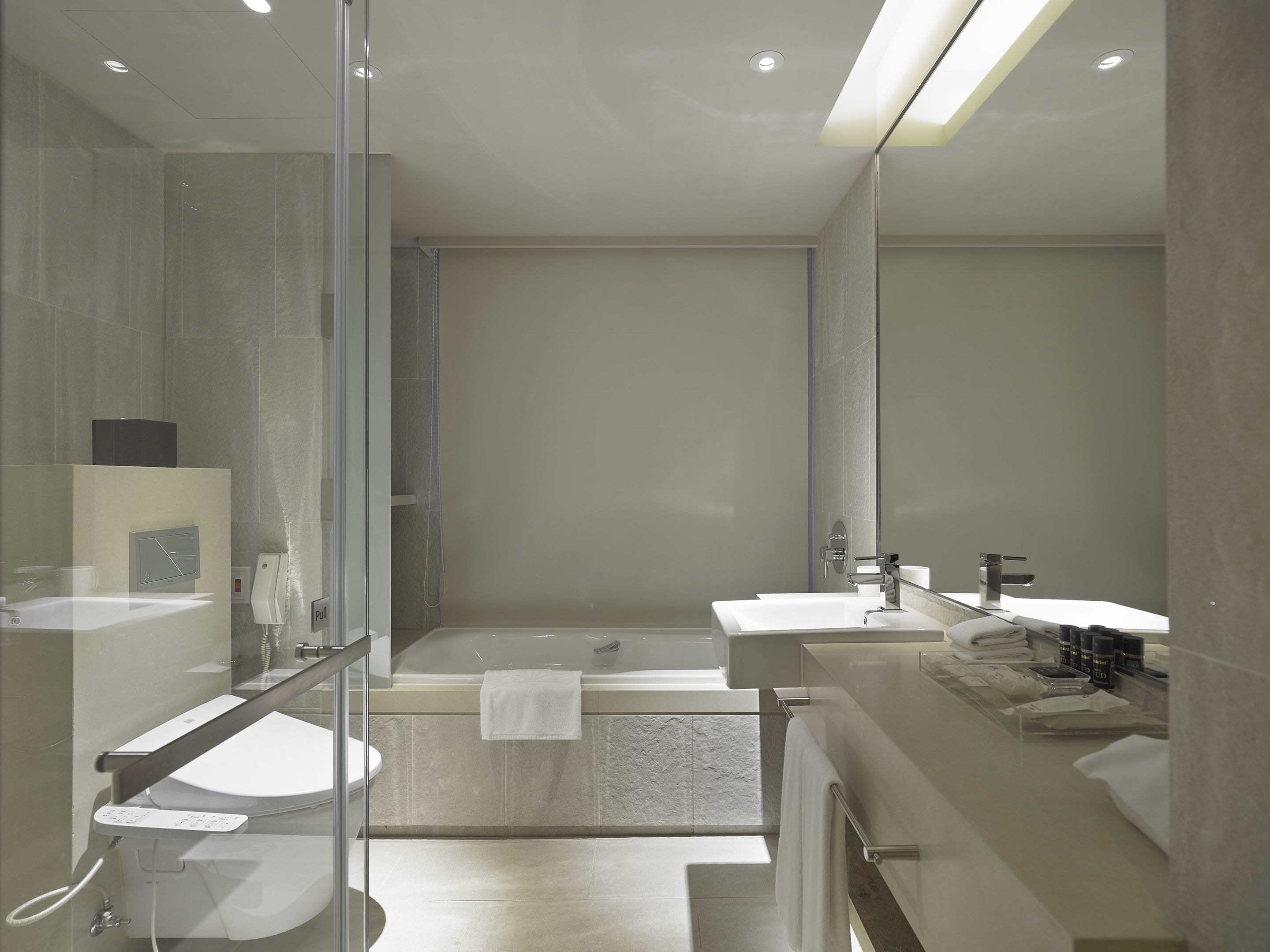 A modern bathroom with a glass shower enclosure, a bathtub, and two sinks.
