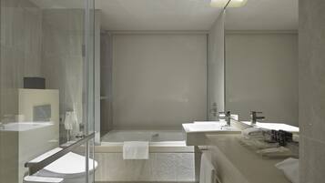 A modern bathroom with a glass shower enclosure, a bathtub, and two sinks.