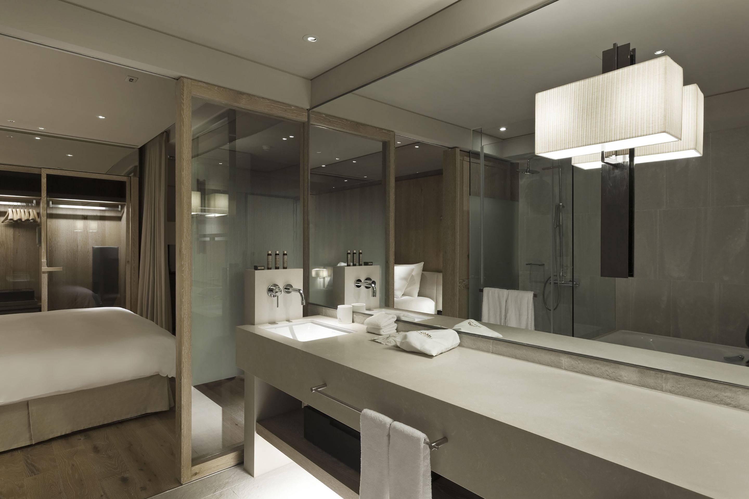 Une salle de bain moderne dotée d’un grand miroir, d’une baignoire, d’une douche et d’un meuble-lavabo avec un évier et un porte-serviettes.